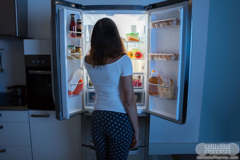 Девушка открывает и смотрит в холодильник